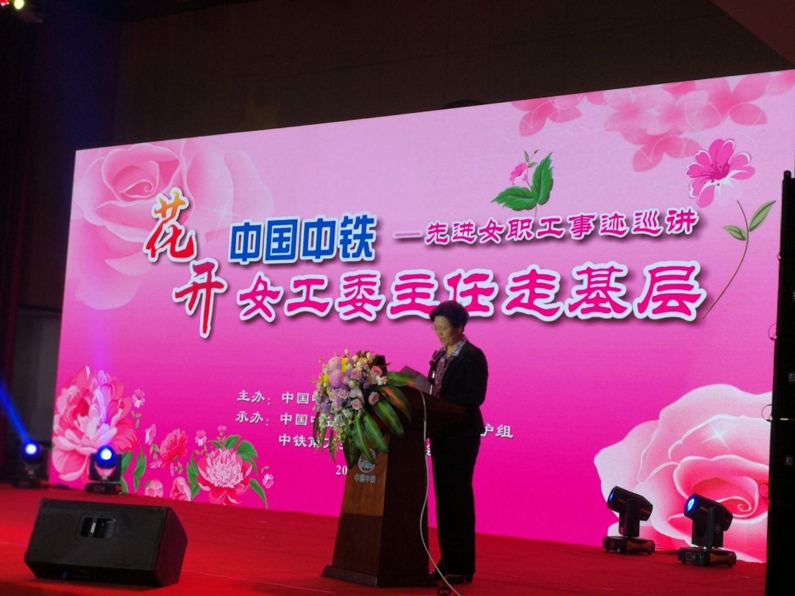 舞台演讲现场：粉色主题大屏与灯光设备