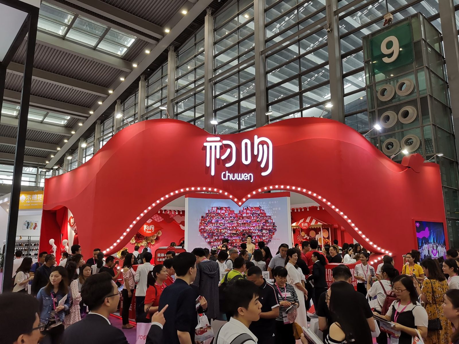 大型展会现场：红色双拱门造型展位与热闹洽谈人群