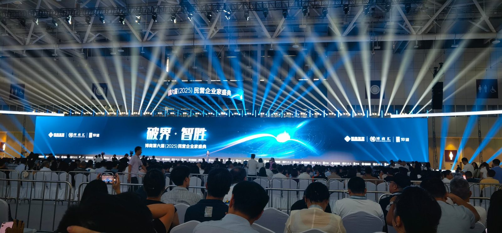 大型会议活动现场：舞台蓝色光束矩阵与主视觉大屏