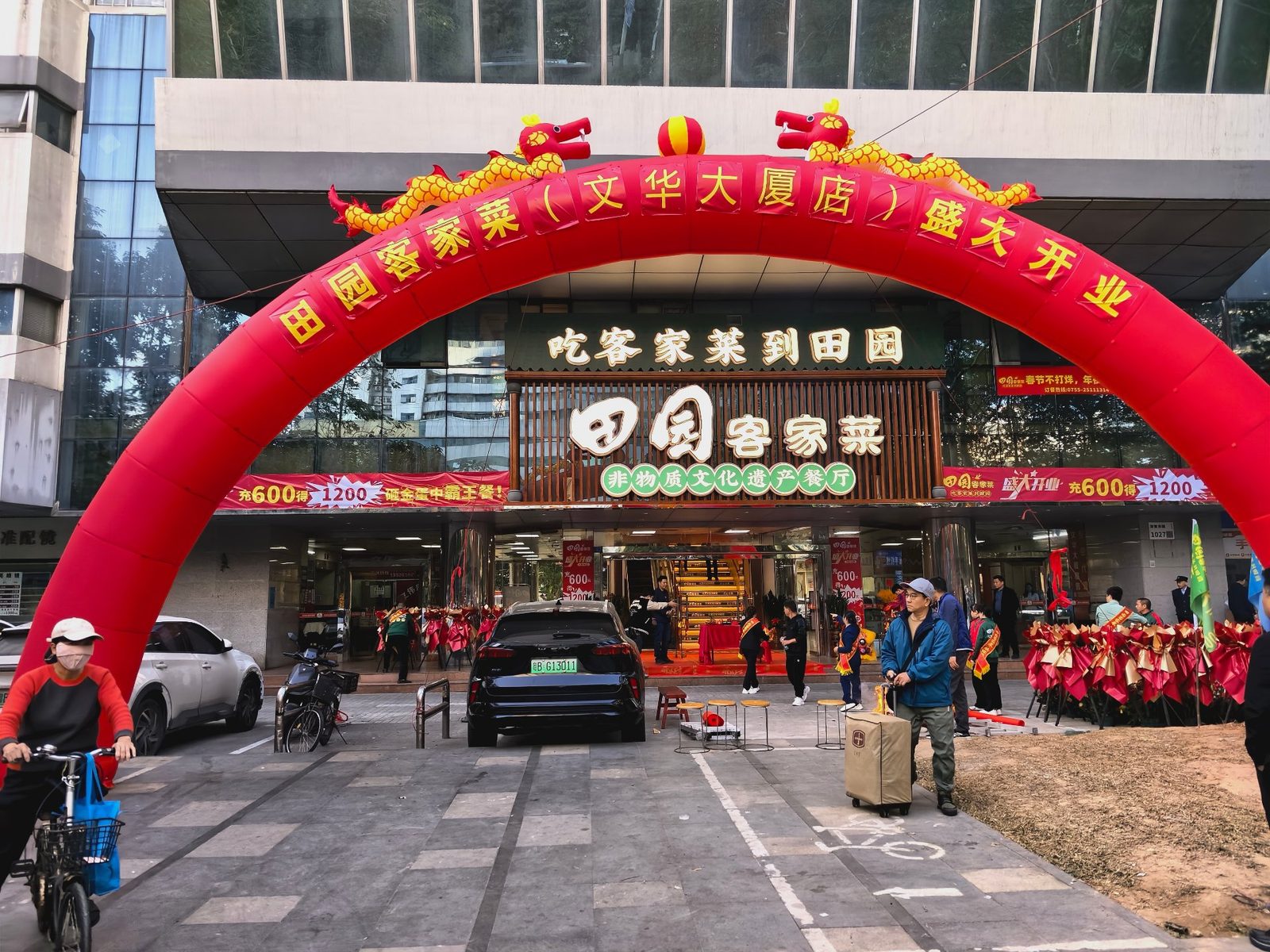 门店开业充气拱门实景：红色双龙拱门下花篮与嘉宾聚集