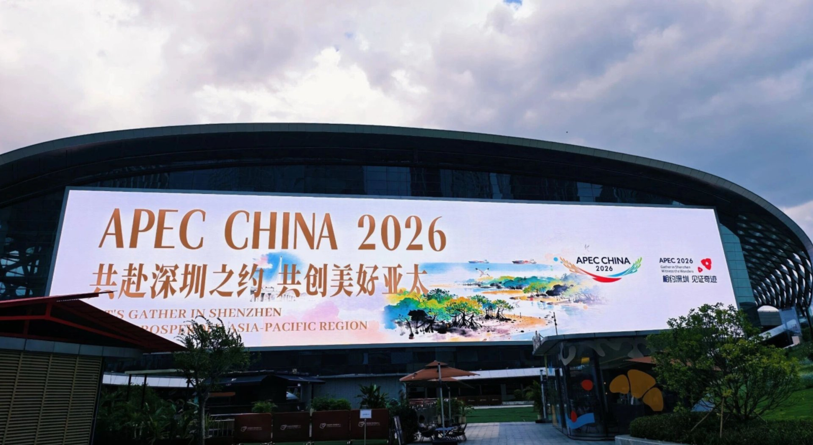 APEC CHINA 2026 深圳主场馆外景：弧形屋顶建筑与巨幅主视觉装置