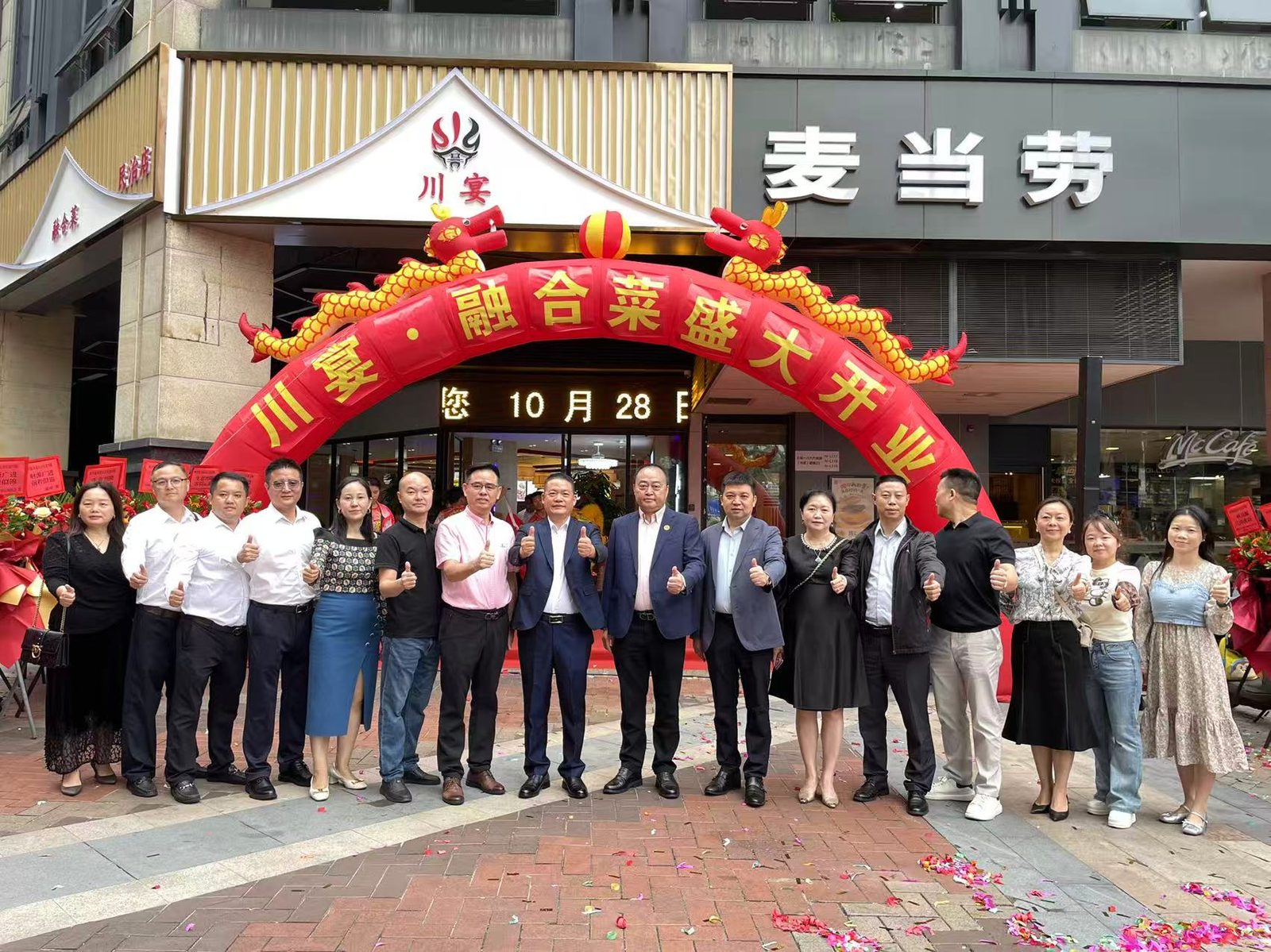 门店开业剪彩合影：红色双龙拱门前嘉宾集体点赞